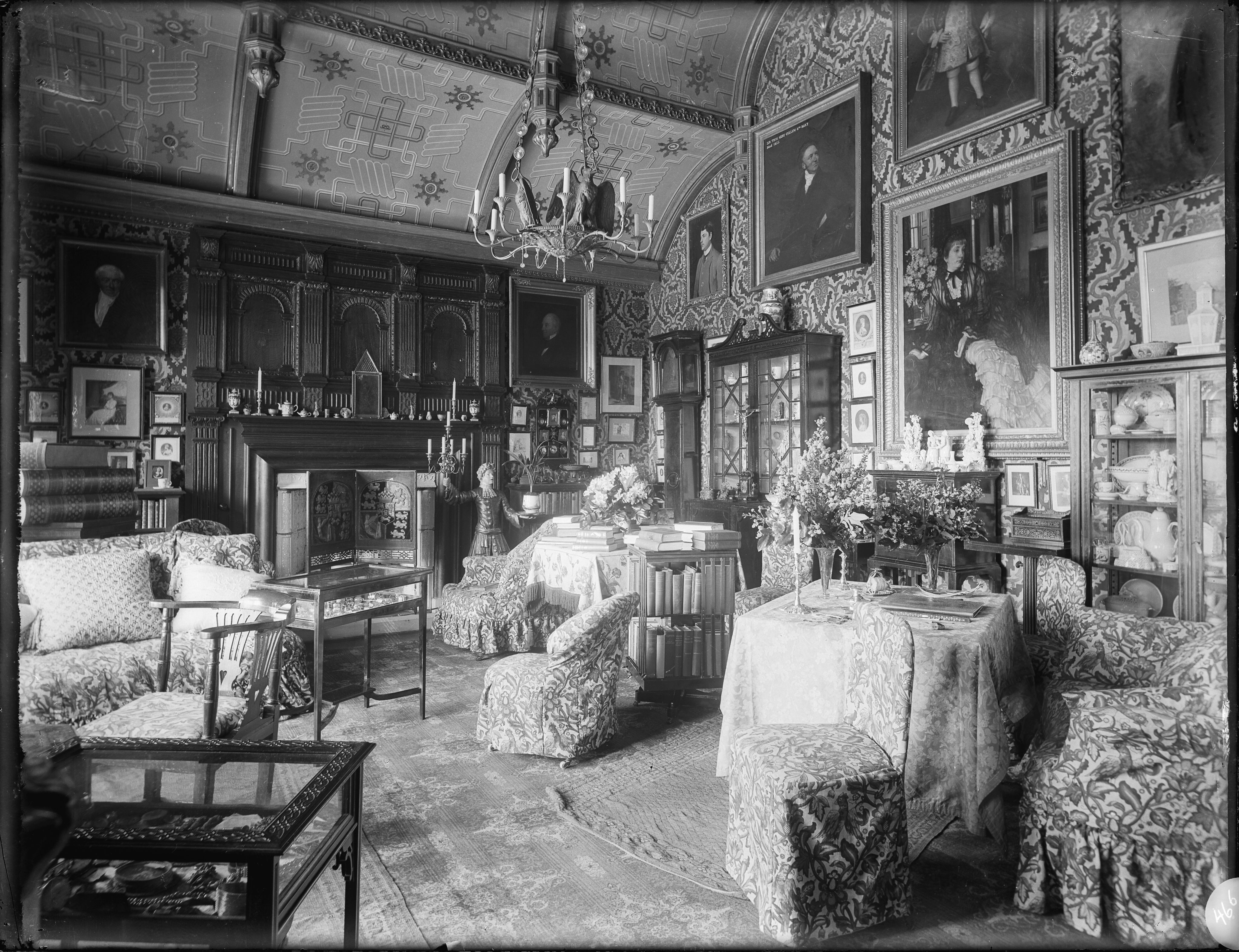 A greyscale image of the interior of the boudoir room in Hardwick House. No surface escaped decoration with chairs, tables, glass cabinets filled with ceramics, and pictures adorning the walls. 
