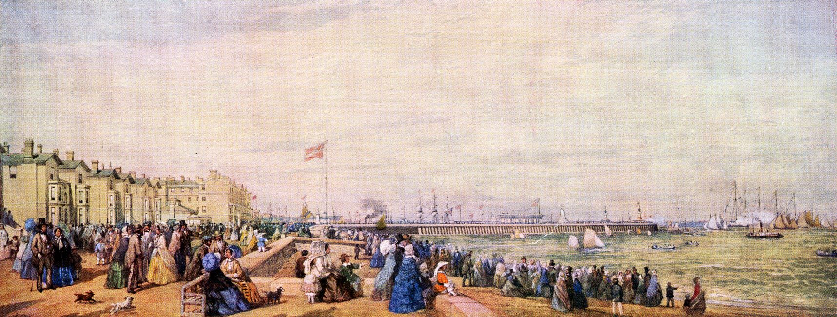 A coloured image of Lowestoft regatta taken in 1855. From right to left: the sea is visible with a number of small sailing yachts present as well as canoes. In the background, a sea wall is viewable and the rigs of larger sailing vessels are viewable over the sea wall. Moving inwards from the sea, hundreds of people are standing on the sand watching the regatta take place – they all are wearing different colours cloths; green, blue, yellows, white, purple and reds. Some are also chatting. They are congregated densely where the sea meets the beach but several are also gathered up to the top of the beach (where the beach ends, and the buildings start). Beyond where the beach ends, are a number of buildings. 