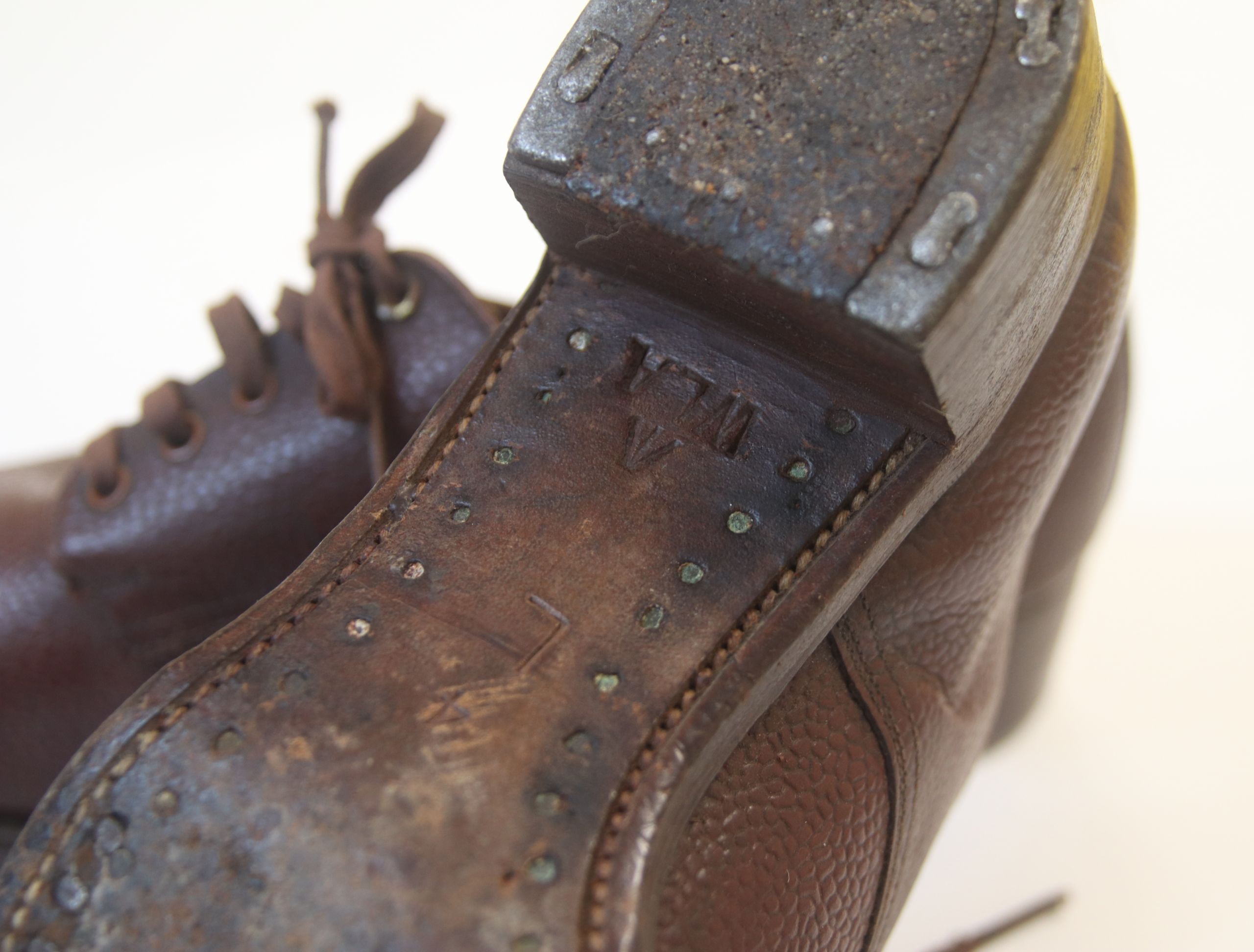 Colour photograph of the sole of the Women's Land Army brown leather shoes. The sole is stamped with the initials WLA.