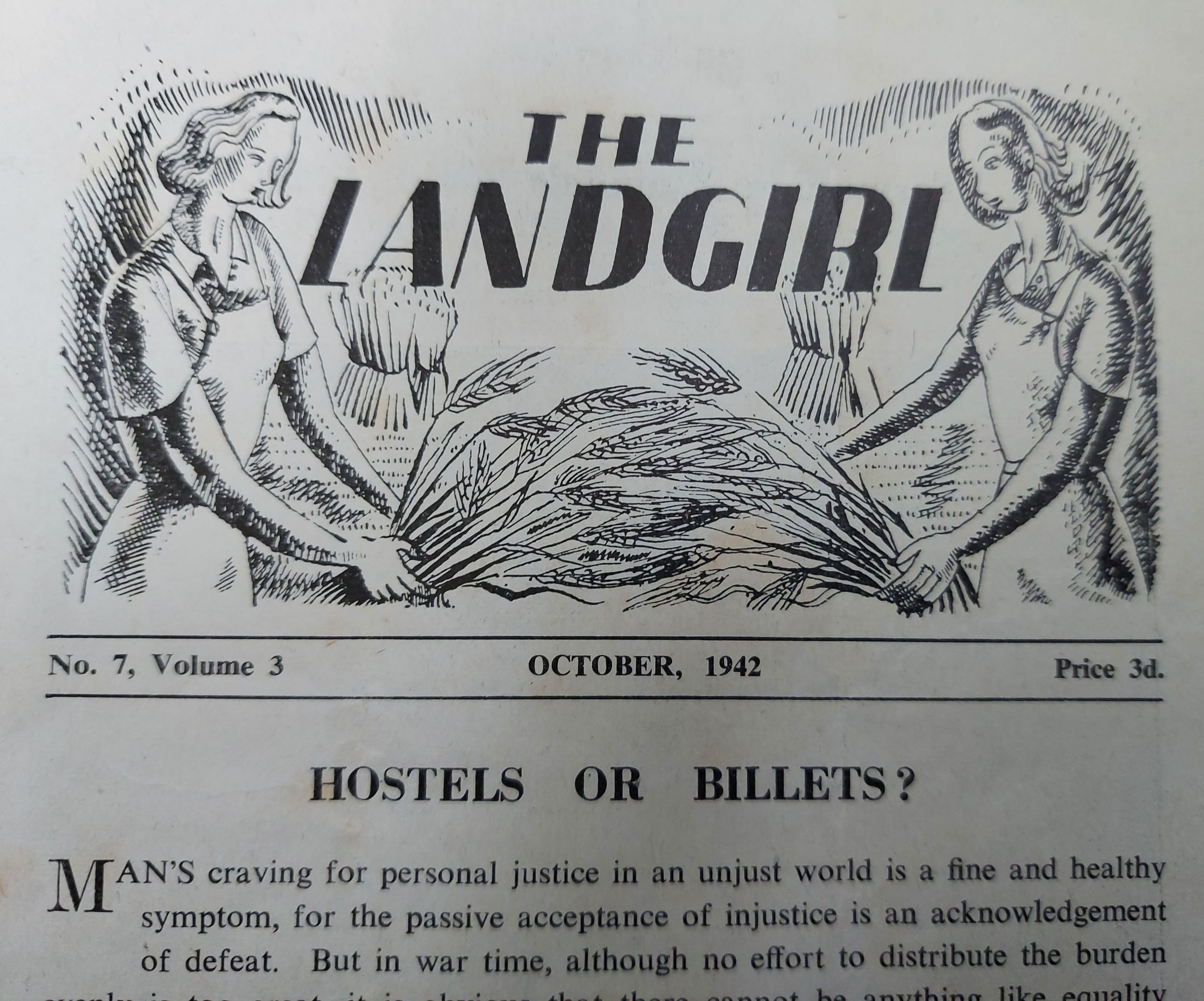 Image of the Land Girl magazine from October 1942. The header image of the magazine is a stylised drawing showing two women harvesting wheat. The headline is 'Hostels or billets?'. This magazine was No. 7, Volume 3, and cost three pence.