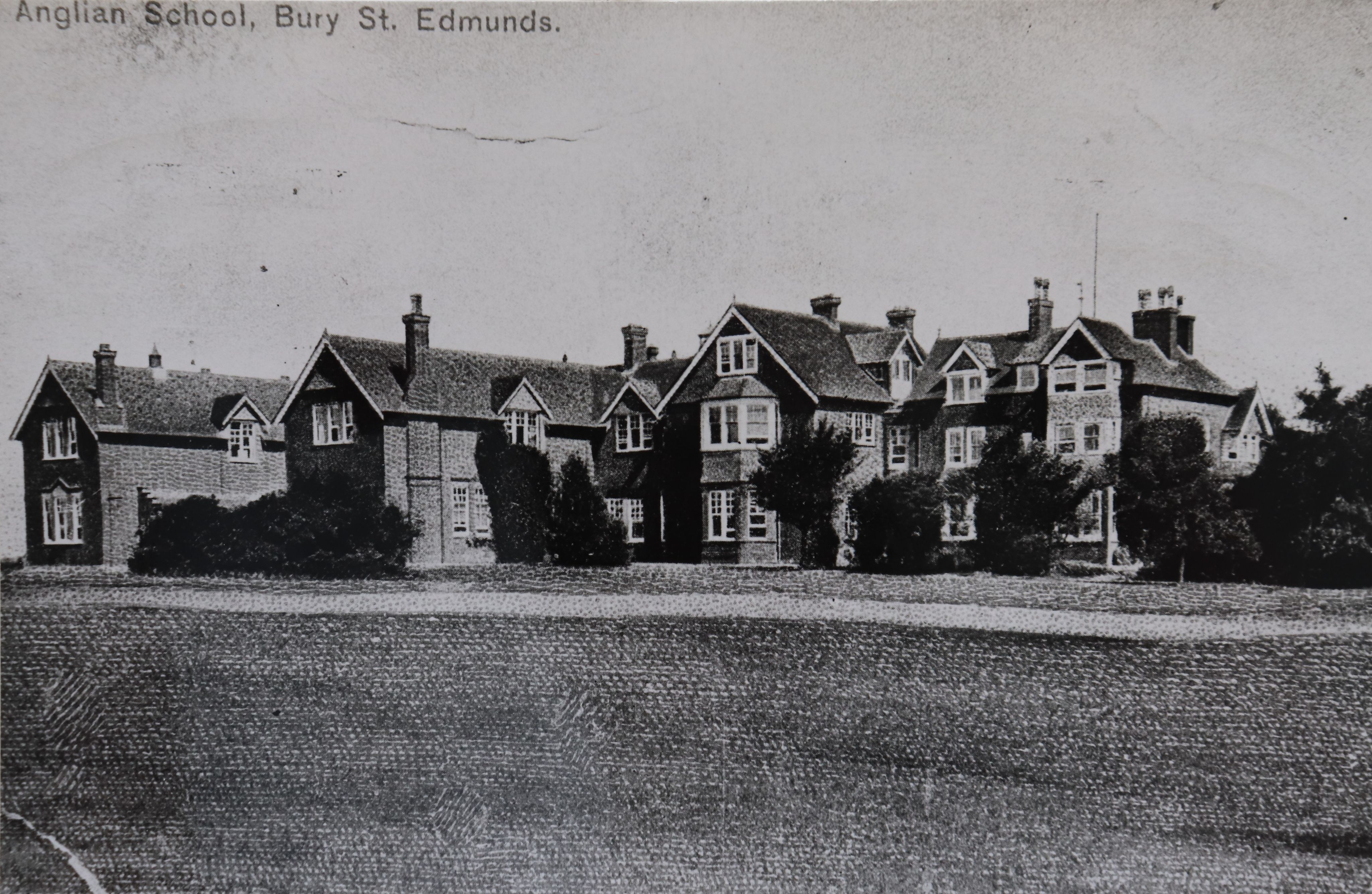 Black and white postcard of a range of red brick buildings